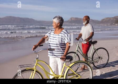 Ein älteres afroamerikanisches Paar mit Fahrrädern, die am Strand stehen Stockfoto