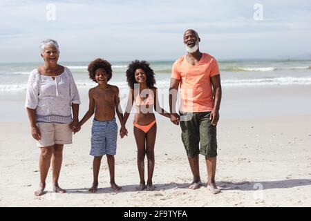 Porträt afroamerikanischer Großeltern und Enkelkinder mit lächelnden Händen Am Strand Stockfoto