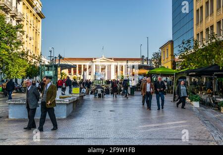 ATHEN, GRIECHENLAND, 10. DEZEMBER 2015: Die Menschen gehen durch eine breite Fußgängerstraße, hinter der sich das Gebäude der Universität von athen befindet Stockfoto