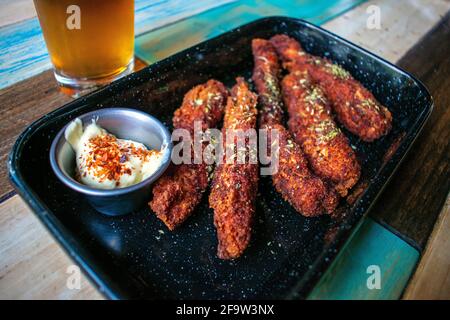 Gebratene Hähnchenstreifen mit Mayonnaise und einem Glas Bier. Stockfoto