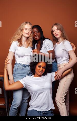 Junge hübsche kaukasische, afro, skandinavische Frau posiert fröhlich zusammen auf braunem Hintergrund, Lifestyle diverse Nationalität Menschen Konzept Stockfoto