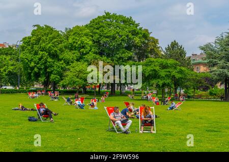 WIEN, ÖSTERREICH, JUNI 2016: Auf einer Liegewiese vor der votivkirche in Wien genießen die Menschen einen sonnigen Tag. Stockfoto