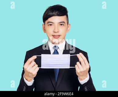 asiatischer Geschäftsmann mit Maske und Blick auf die Kamera Stockfoto