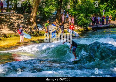 MÜNCHEN, 20. AUGUST 2015: Eine Gruppe Surfer übt ihr Können auf einer künstlichen Welle, die auf einem kleinen Kanal im Zentrum von münchen liegt Stockfoto