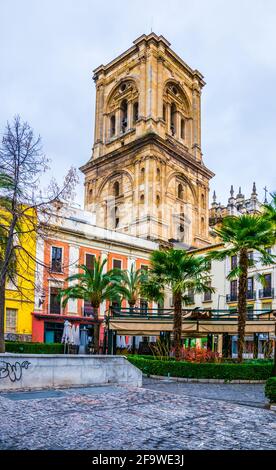 GRANADA, SPANIEN, 3. JANUAR 2016: Blick auf eine Straße mit bunten Häusern, die vom Turm der Inkarnationskathedrale in granada, spanien, dominiert wird Stockfoto