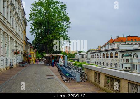 LJUBLJANA, SLOWENIEN, 29. Juli 2015: Die Menschen gehen entlang der Petkovskovo Waterfront mit Geschäften und Restaurants vor dem Marktplatz und der Metzgerbrücke Stockfoto