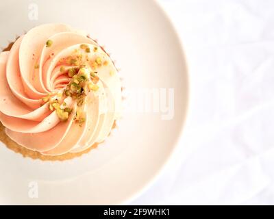 Hübscher Cupcake mit pinkem Zuckerguss aus nächster Nähe auf einem weißen Hintergrund Stockfoto