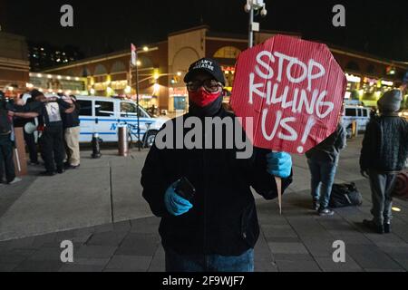 Brooklyn, New York, USA 20 Apr 2021. Der Mann hält das Schild „Stoppen Sie, uns zu töten“, während sich Demonstranten am Barclays Center Stunden versammeln, nachdem eine Jury den ehemaligen Minneapolis-Polizeibeamten Derek Chauvin für schuldig befunden hat, 2020 George Floyd ermordet zu haben. Stockfoto