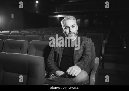 Eleganter männlicher Theater- und Filmregisseur, der ein Interview gibt Hintergrund des Auditoriums Stockfoto