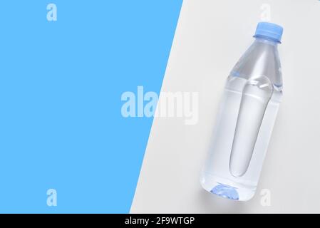 Plastikflasche mit Wasser auf weißem und blauem Hintergrund Stockfoto