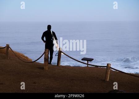 Surfer Walking zum Surfen, Blue Hour, Surfbrett und Neoprenanzug, Sonnenaufgang, in punta de lobos Pichilemu Stockfoto