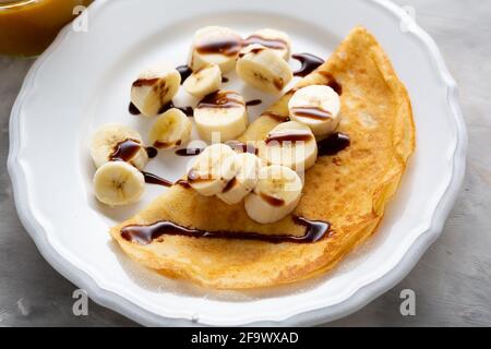 Nahaufnahme von Crepes mit Banane auf weißem Teller Stockfoto