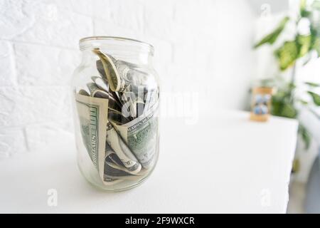 Faltet Geld in einem Glas auf einem weißen Holzhintergrund. Der Ort des Hintergrundbildes für Text. Stockfoto