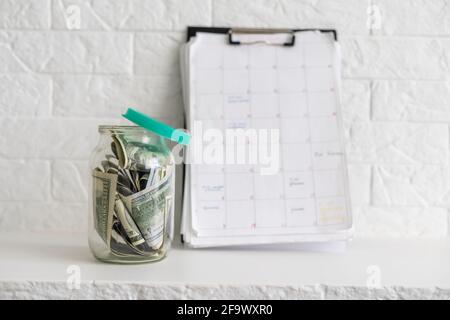 Faltet Geld in einem Glas auf einem weißen Holzhintergrund. Der Ort des Hintergrundbildes für Text. Stockfoto