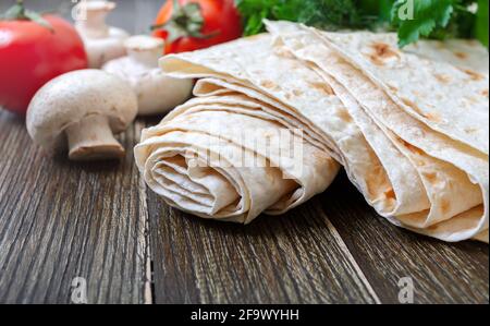 Dünnes Pita-Brot mit frischem Gemüse auf Holzboden. Lavasch - leckeres herzhaftes gesundes armenisches und türkisches ungesäuertes Fladenbrot. Kopieren Sie die Spase Stockfoto