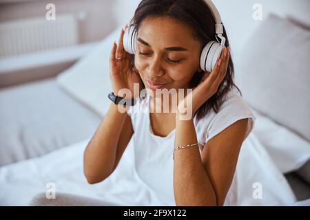 Attraktive junge Frau, die zu Hause Musik hört Stockfoto