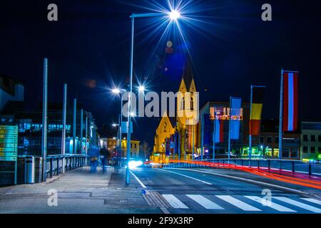 VILLACH, ÖSTERREICH, 20. FEBRUAR 2016: Nachtansicht einer Brücke über die drau mit Turm der nikolaikirche in villach, österreich. Stockfoto