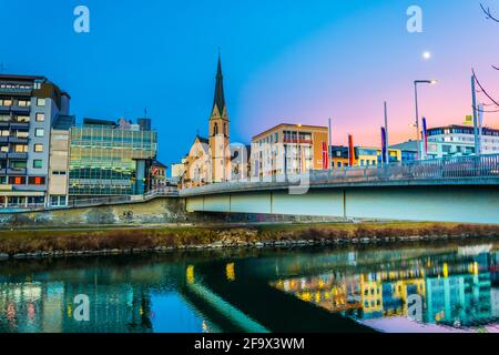 VILLACH, ÖSTERREICH, 20. FEBRUAR 2016: Blick auf eine Brücke über die drau mit Turm der nikolaikirche in villach, österreich. Stockfoto