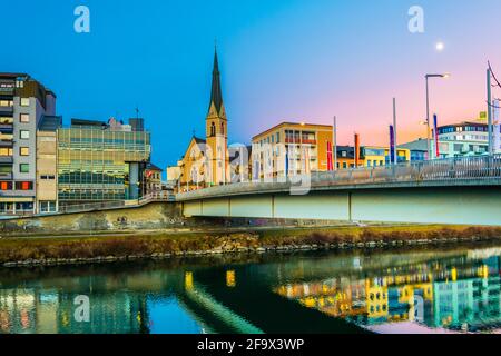 VILLACH, ÖSTERREICH, 20. FEBRUAR 2016: Blick auf eine Brücke über die drau mit Turm der nikolaikirche in villach, österreich. Stockfoto