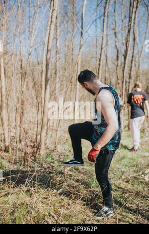 Vertikale Aufnahme eines jungen kaukasischen Mannes, der Zweige sammelt Ein Wald während des Picknicks Stockfoto