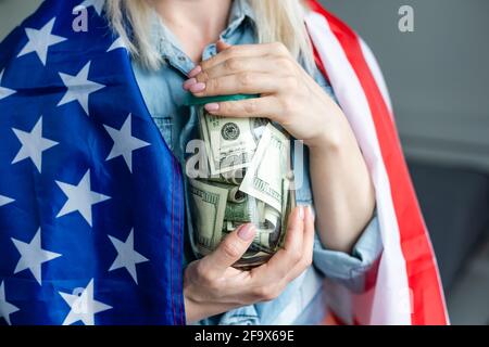 Frau mit Dollars im Glasgefäß und amerikanischer Flagge Stockfoto