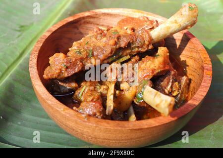 Hammelfleisch zerkleinert das urige. Indisches rustikales würziges, nicht-vegetarisches Ziegenfleisch-Indische, in einer Holzschüssel über einem Bananenblatt-Hintergrund servierte, Platz zum Kopieren. Stockfoto