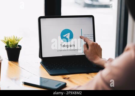 CHIANG MAI, THAILAND, MAR 21, 2021 : Frau Hand mit iPad Pro mit Social-Networking-Service Telegram auf dem Bildschirm. IPhone 10 wurde erstellt und Stockfoto