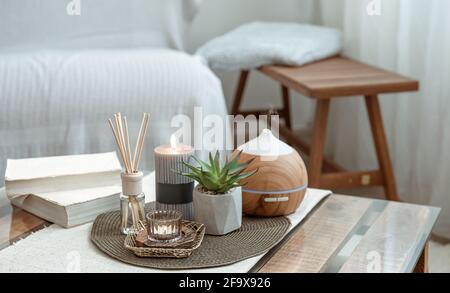 Komposition mit Räucherstäbchen, Diffusor, Kerzen und Büchern auf dem Tisch im Innenraum des Raumes. Stockfoto