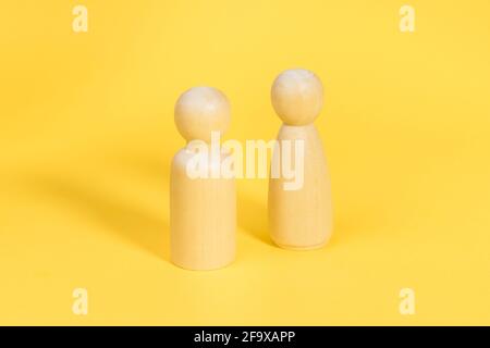 Holzfiguren von Mann und Frau auf gelbem Hintergrund, Beziehung, Kommunikationsprobleme. Stockfoto