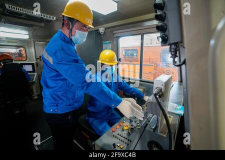 (210421) -- URUMQI, 21. April 2021 (Xinhua) -- Niu Ruiqing (L) gibt am 3. März 2021 seinem Kollegen in der Abteilung für Instandhaltung von Gleis- und Maschinen in Urumqi, der Autonomen Region Xinjiang Uygur im Nordwesten Chinas, die Richtung vor. Eine Karriere-Staffel von drei Generationen über 70 Jahre innerhalb derselben Familie hat die erstaunliche Entwicklung des Eisenbahnverkehrs in der Autonomen Region Xinjiang Uygur im Nordwesten Chinas erlebt. Xinjiang ist seit jeher bekannt für seine raue geologische und klimatische Umgebung, die von riesigen Wüsten, schneebedeckten Bergen, verheerenden Winden bis hin zu salzigen Sümpfen reicht Stockfoto