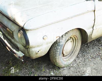 Fragment eines alten schmutzigen weißen Autos, das auf dem Boden stand Stockfoto