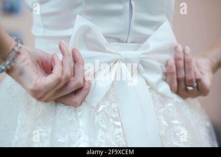 Nahaufnahme der Braut, die ihren Bogen auf sie fixiert Weißes Hochzeitskleid Stockfoto