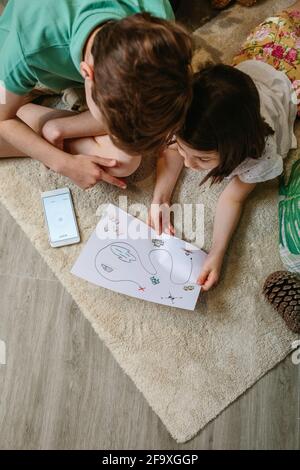Draufsicht auf Kinder, die zu Hause auf Schatzsuche spielen Der Teppich Stockfoto
