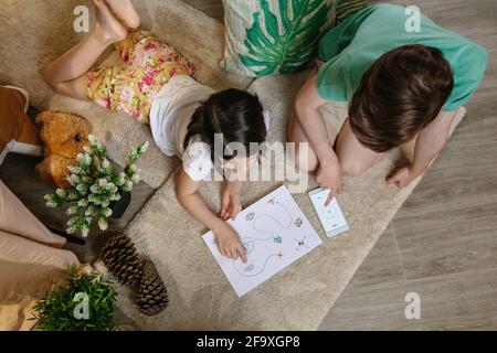 Nicht erkennbare Kinder, die zu Hause auf dem Teppich Schatzsuche spielen Stockfoto