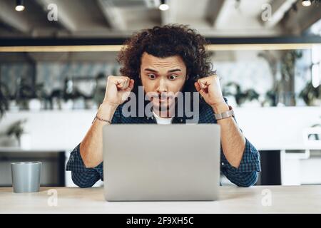 Aufgeregt überglücklich jungen Geschäftsmann Blick auf Laptop-Bildschirm glücklich zu Gewinnen oder gute Nachrichten erhalten Stockfoto