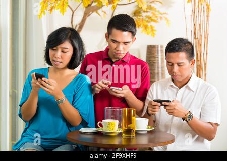 Asiaten Spaß zusammen mit Handy und trinken Kaffee oder cocktail Stockfoto
