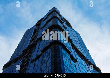 Mehrstöckiges modernes Wohngebäude aus Glas vor dem Hintergrund des bewölkten Himmels. Stockfoto