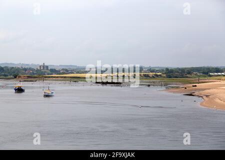 Fischerboote auf dem River Coquet in Amble in Northumberland, England. Warkwarth Castle blickt auf die Flussmündung. Stockfoto