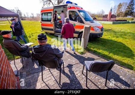 21. April 2021, Mecklenburg-Vorpommern, Kirchdorf (poel): Bewohner der Ostseeinsel Poel sitzen auf dem Freigelände des Inselmuseums vor einem Krankenwagen und warten auf ihre Corona-Impfung mit BioNTech-Impfstoff. Ein neues Konzept für Corona-Impfungen soll auf der Insel gemeinsam mit der Bundeswehr getestet werden. Das Impfteam besteht aus einem Arzt, einem Facharzt und vier Mitgliedern der Bundeswehr. Foto: Jens Büttner/dpa-Zentralbild/dpa Stockfoto