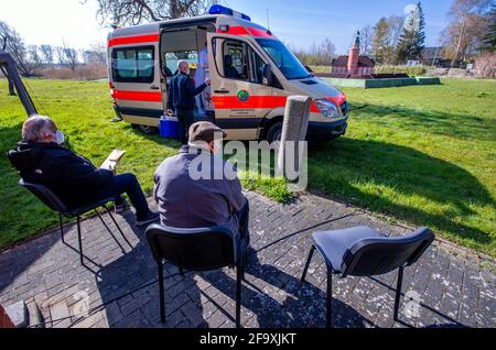 21. April 2021, Mecklenburg-Vorpommern, Kirchdorf (poel): Bewohner der Ostseeinsel Poel sitzen auf dem Freigelände des Inselmuseums vor einem Krankenwagen und warten auf ihre Corona-Impfung mit BioNTech-Impfstoff. Ein neues Konzept für Corona-Impfungen soll auf der Insel gemeinsam mit der Bundeswehr getestet werden. Das Impfteam besteht aus einem Arzt, einem Facharzt und vier Mitgliedern der Bundeswehr. Foto: Jens Büttner/dpa-Zentralbild/dpa Stockfoto