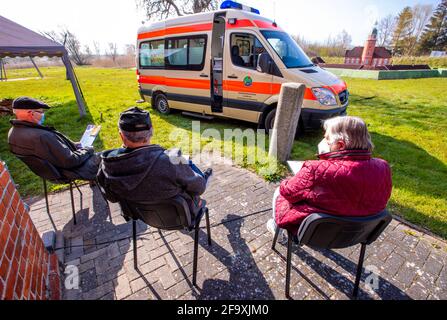 21. April 2021, Mecklenburg-Vorpommern, Kirchdorf (poel): Bewohner der Ostseeinsel Poel sitzen auf dem Freigelände des Inselmuseums vor einem Krankenwagen und warten auf ihre Corona-Impfung mit BioNTech-Impfstoff. Ein neues Konzept für Corona-Impfungen soll auf der Insel gemeinsam mit der Bundeswehr getestet werden. Das Impfteam besteht aus einem Arzt, einem Facharzt und vier Mitgliedern der Bundeswehr. Foto: Jens Büttner/dpa-Zentralbild/dpa Stockfoto