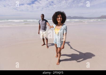 afroamerikanisches Paar, das am Strand läuft und die Hände hält Lächelnd Stockfoto