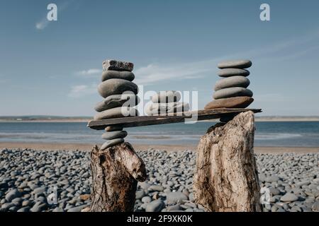 Eine Strandskulptur eines Turms aus Kieselsteinen, gestapelt auf Treibholz in Westward Ho! Beach, Devon, Großbritannien Stockfoto