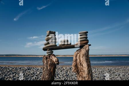 Eine Strandskulptur eines Turms aus Kieselsteinen, gestapelt auf Treibholz in Westward Ho! Beach, Devon, Großbritannien Stockfoto