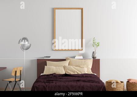 Ein vertikaler, leerer Posterrahmen ist an der weißen Wand im Inneren des modernen Schlafzimmers nachempfunden Stockfoto