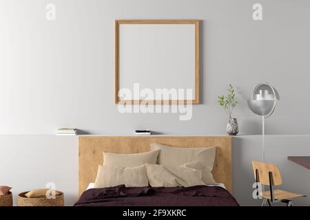 Ein quadratischer, leerer Posterrahmen ist an der weißen Wand im Inneren des modernen Schlafzimmers nachempfunden Stockfoto