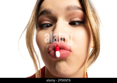 Nahaufnahme einer jungen Frau, die Lippen mit isolierter Kapsel ausschüttet Auf Weiß Stockfoto