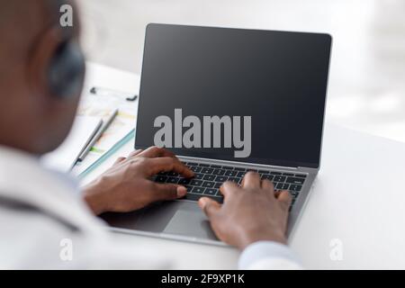 Online-Konferenz. afroamerikanischer Arzt mit Laptop mit leerem Bildschirm, leerem Raum Stockfoto