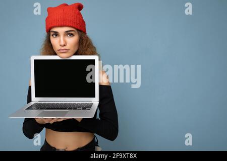 Nahaufnahme Porträt von lustigen schönen dunklen blonden Frau mit Laptop Computer mit Blick auf die Kamera mit schwarzem Crop-Top und rot Und orange do-RAG Stockfoto