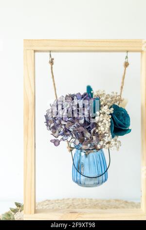 Getrocknete Blumen in Glasbehälter innerhalb eines Rahmens als Dekorationsmotiv Stockfoto